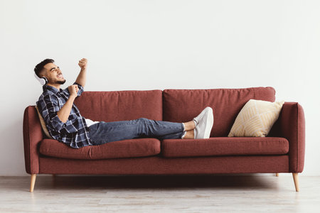 Man Listens to Music on Couch and Enjoys the Moment in an Indoor Spaceの写真素材