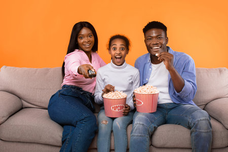 Family Enjoys Movie Night Together With Popcorn and Remote in a Cozy Setting