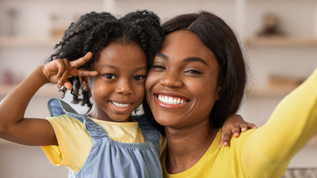 Smiling Mother and Daughter Pose Happily for a Cheerful Moment During Daytime Indoors