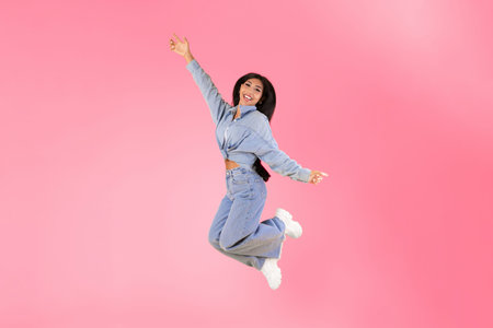 Excited young woman jumping up at orange studio