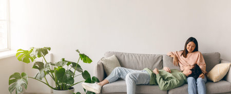 Couple Relaxing Together on a Couch in a Bright Living Room With Plants and Natural Lightの写真素材