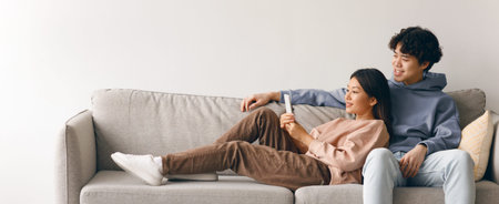 Couple Relaxing Together on a Couch While Using a Mobile Device in a Cozy Living Room Settingの写真素材