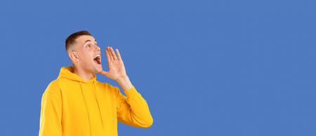 Positive caucasian man yelling towards copy space, holding hand next to mouth, making announcement