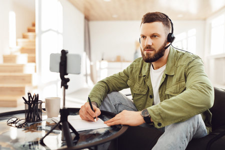 Man Taking Notes Making Video Call Via Smartphone Indoorの写真素材