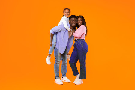 Family Enjoys Fun Together With Bright Orange Background and Joyful Expressions in Studio Setting