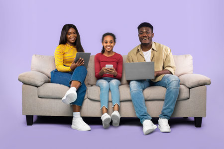Family Enjoys Time Together With Devices on a Couch in a Purple Room