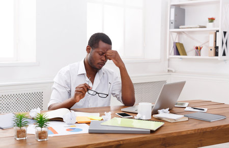 Tired african-american employee at workplace