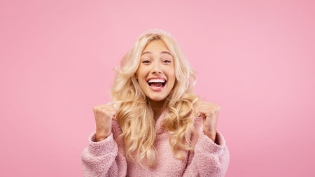 Young Woman Expresses Joy in Front of Pink Background During a Lively Momentの写真素材