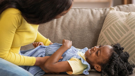 Mother and Daughter Share a Playful Moment on the Couch at Homeの写真素材