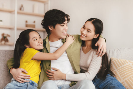 Satisfied young korean family hugging and enjoying rest, free time on weekendの写真素材