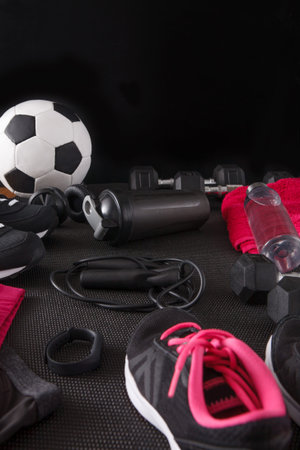 Equipment for Sports and Workouts Arranged on Black Background With Soccer Ball and Weights