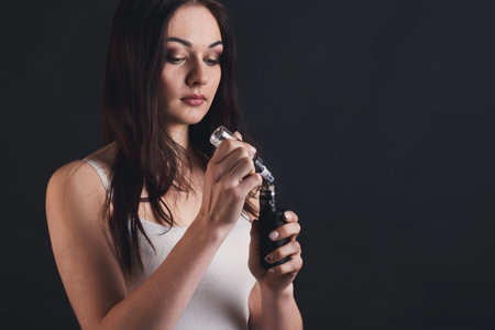 Woman Holding a Vape Device While Preparing to Take a Puff in a Studio Settingの写真素材
