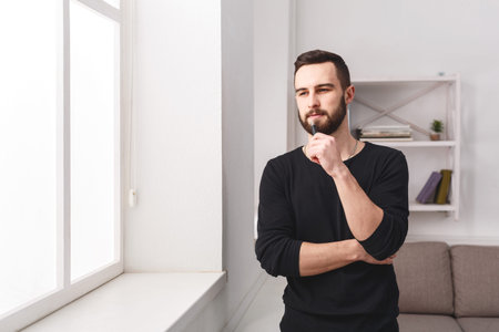 Man Thinking by Window in Modern Room During Daytime