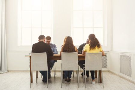 Group of People Sitting Around a Table in a Bright Room During a Meeting or Discussion