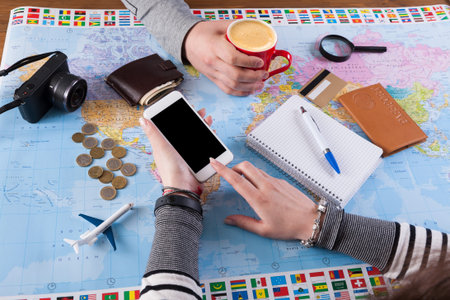 Planning a Trip With Maps, Coffee, and a Smartphone While Enjoying Travel Items on the Table