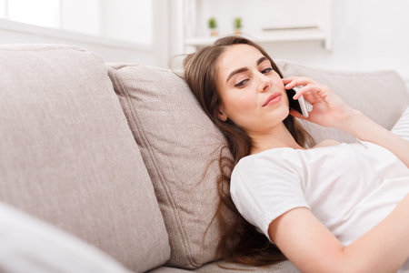 Woman Talking on Phone While Relaxing on Couch in Cozy Living Room During the Day