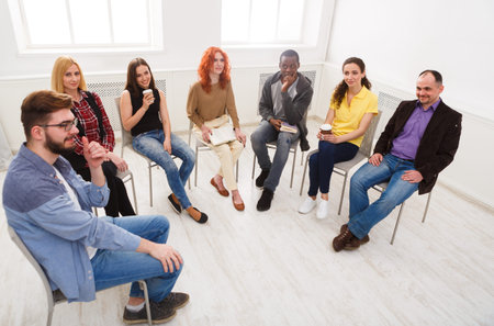 Group of People Sitting in a Circle in a Room Having a Discussion During a Meeting
