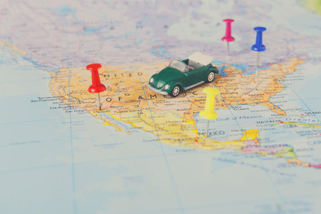 Small Green Car Model on a Map of the Southern United States With Colorful Push Pins Set in Place