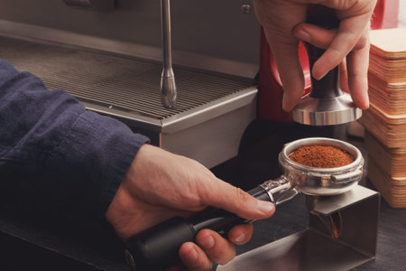 Barista Tamps Coffee in Portafilter at Espresso Machine in Cafe During Morning Shift