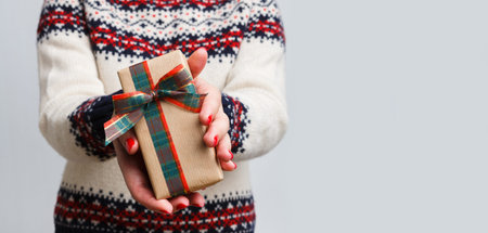 Gift Giving During the Holiday Season With a Festive Sweater and Wrapped Present in Handsの写真素材