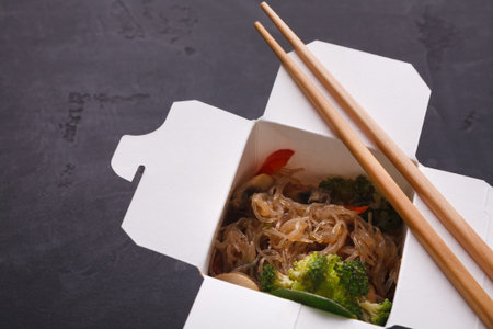 Collection of Food in a Box With Chopsticks and Vegetables on Dark Background