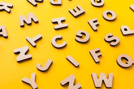 Wooden Letters Scattered on a Bright Yellow Background in a Creative Workspace