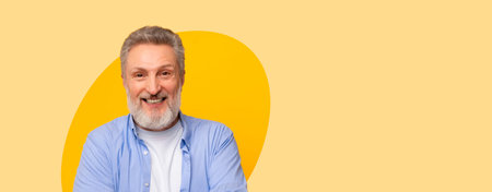 Man With Gray Beard Smiles and Poses in Front of a Yellow Background During a Casual Moment