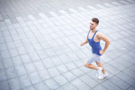 Man Runs on a Paved Surface During the Day in a City Setting With Clear Skies Overhead