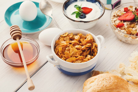 Breakfast Spread With Various Dishes Including Cereal, Yogurt, and Eggs Served on a Wooden Table