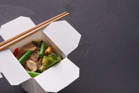 Collage of a Takeout Box With Vegetables and Chopsticks on a Dark Surface
