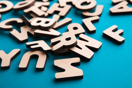 Wooden Letters Scattered on a Blue Background Showing Different Shapes and Sizesの写真素材
