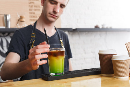 Barista Prepares Colorful Drink in Cafe With Takeaway Cups on Counter During Afternoon Rush
