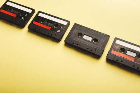 Collection of Cassette Tapes Arranged in a Row on a Yellow Background Showing Vintage Music Historyの写真素材