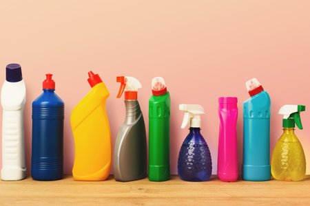 Cleaning Supplies Collection Displayed on a Wooden Surface Against a Light Pink Backgroundの写真素材