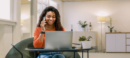 Woman Working on Laptop and Talking on the Phone in a Modern Room During the Day