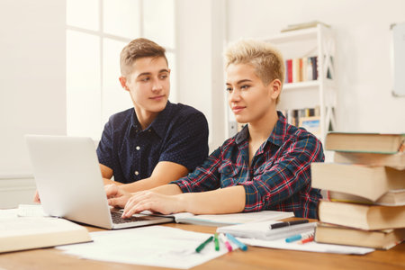 Group of Students Studying and Working Together on a Laptop at a Desk in a Classroom