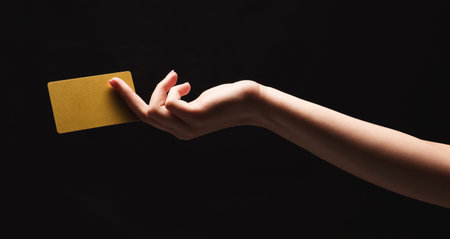 Hand Holding a Yellow Card Against a Dark Background in a Creative Collage or Setの写真素材