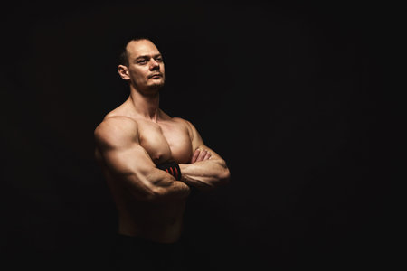 Muscular Man Posing Confidently in a Dark Setting for a Fitness Collection