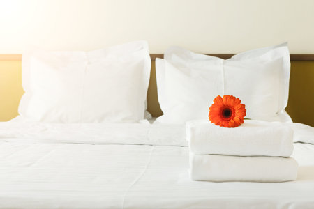Collection of Towels and a Flower on a Bed in a Simple Room Setting Near the Wallの写真素材