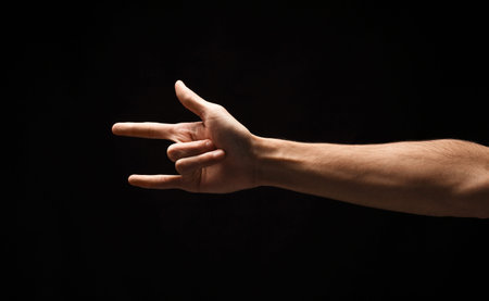 Hand Gesture Shows Sign of Love and Rock Music Culture in Dark Settingの写真素材