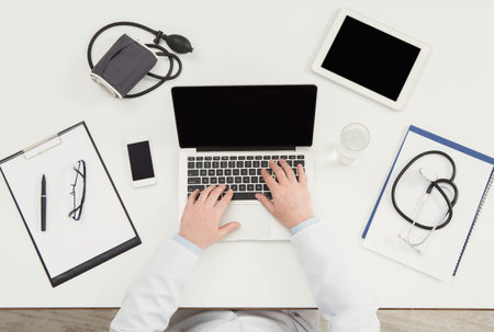 Doctor Working on Laptop While Using Various Tools for Health Monitoring and Patient Care
