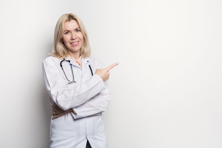 Doctor in White Coat Points to Empty Space in Clean Setting, Suggesting Information or Guidanceの写真素材