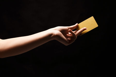 Collection of Images Showing a Hand Holding a Simple Gold Card on a Dark Backgroundの写真素材