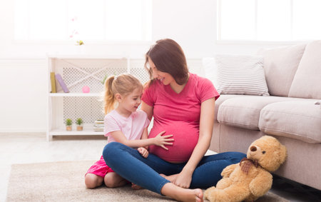 Mother and Daughter Bond While Waiting for the New Baby in a Cozy Living Room Setting
