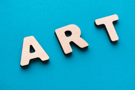 Wooden Letters Spelling Art on a Blue Background During a Crafting Sessionの写真素材