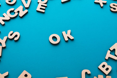 Various Wooden Letters Scattered on a Bright Blue Surface With the Letters OK in the Centerの写真素材