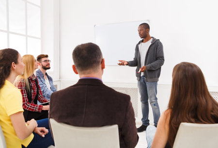 Group of People Listening to a Speaker During a Small Meeting in a Bright Room