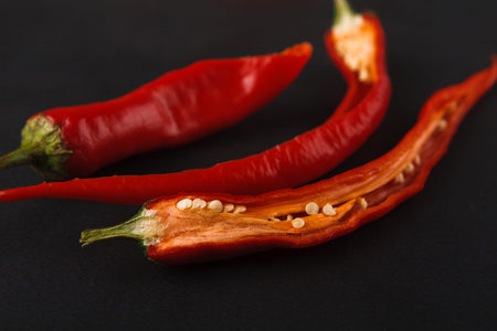 Collection of Red Chili Peppers on a Dark Surface With Some Sliced Open