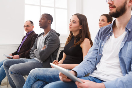 Group of People Seated in a Room During a Meeting in the Morning With Tablets in Their Hands