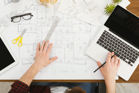 Planning a Building Layout With Tools and Devices on a Wooden Table in an Office Setting